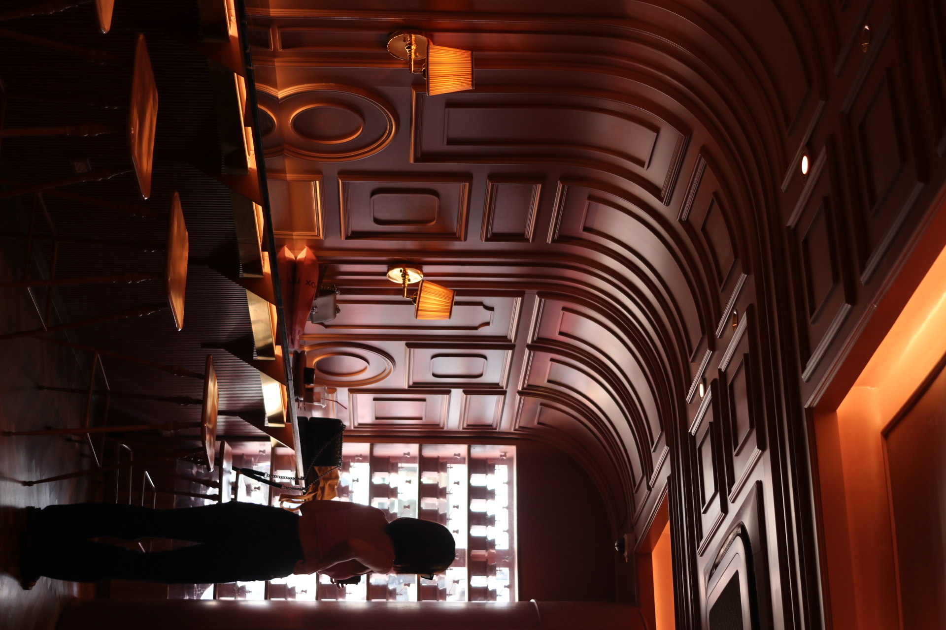 Silhouette of a guest beside the bar — warm dusk light across moulded walls