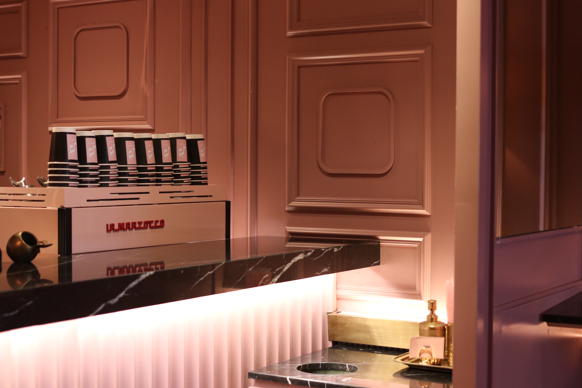 La Marzocco espresso machine on a black marble counter against terracotta panels
